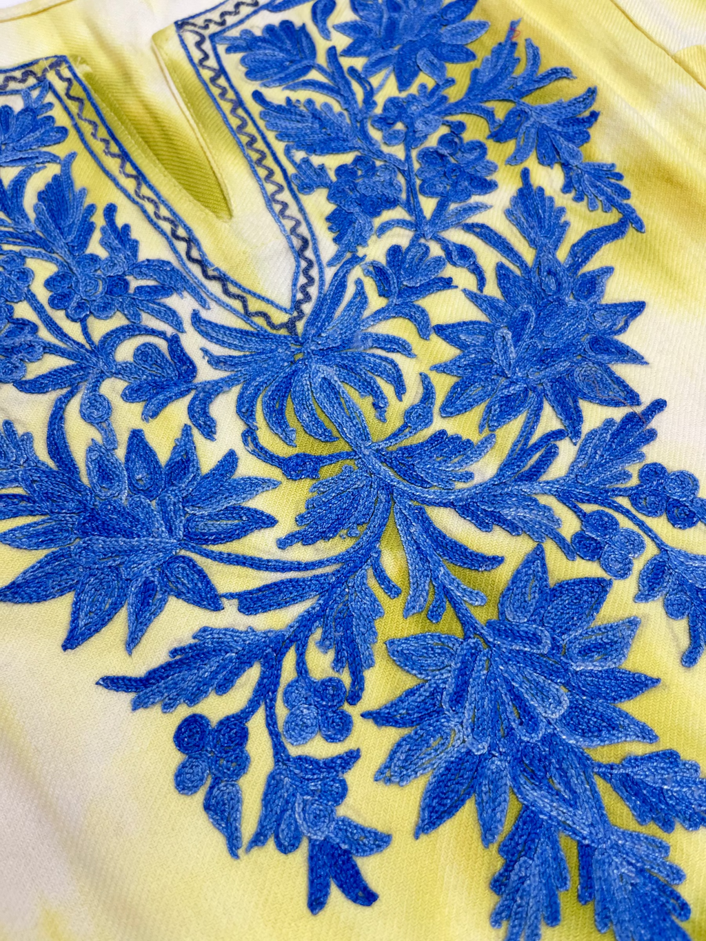 Close-up of a lime green pheran with blue floral embroidery